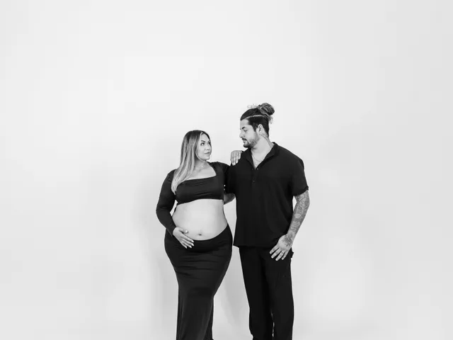 A couple in black at a maternity session on a white seamless backdrop