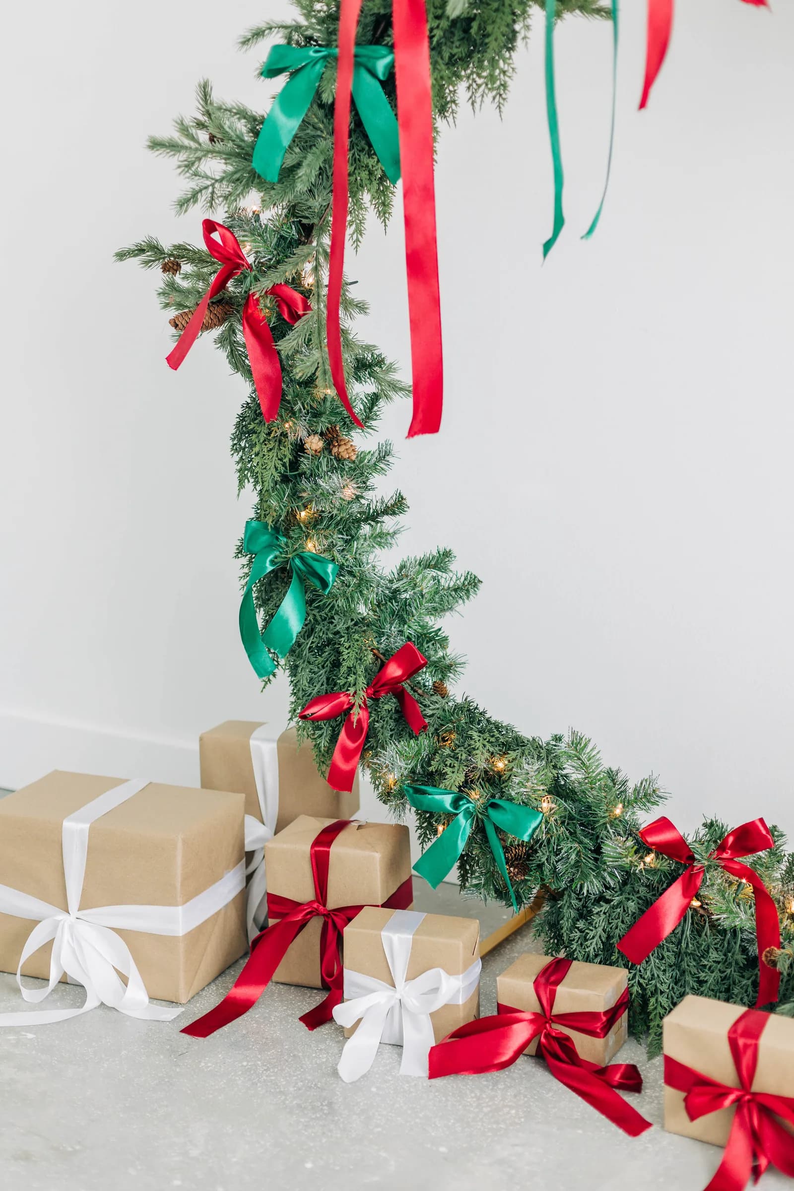 The ribboned wreath curving down to a stack of kraft paper presents on polished concrete