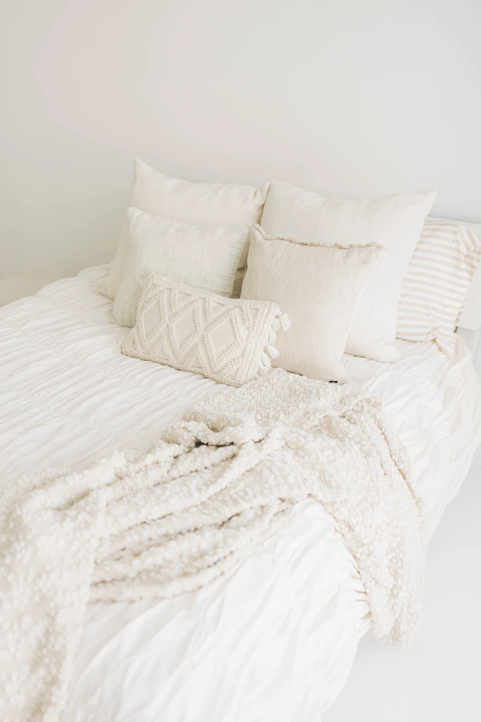 Layered pillows and a chunky knit throw on Studio A's bed