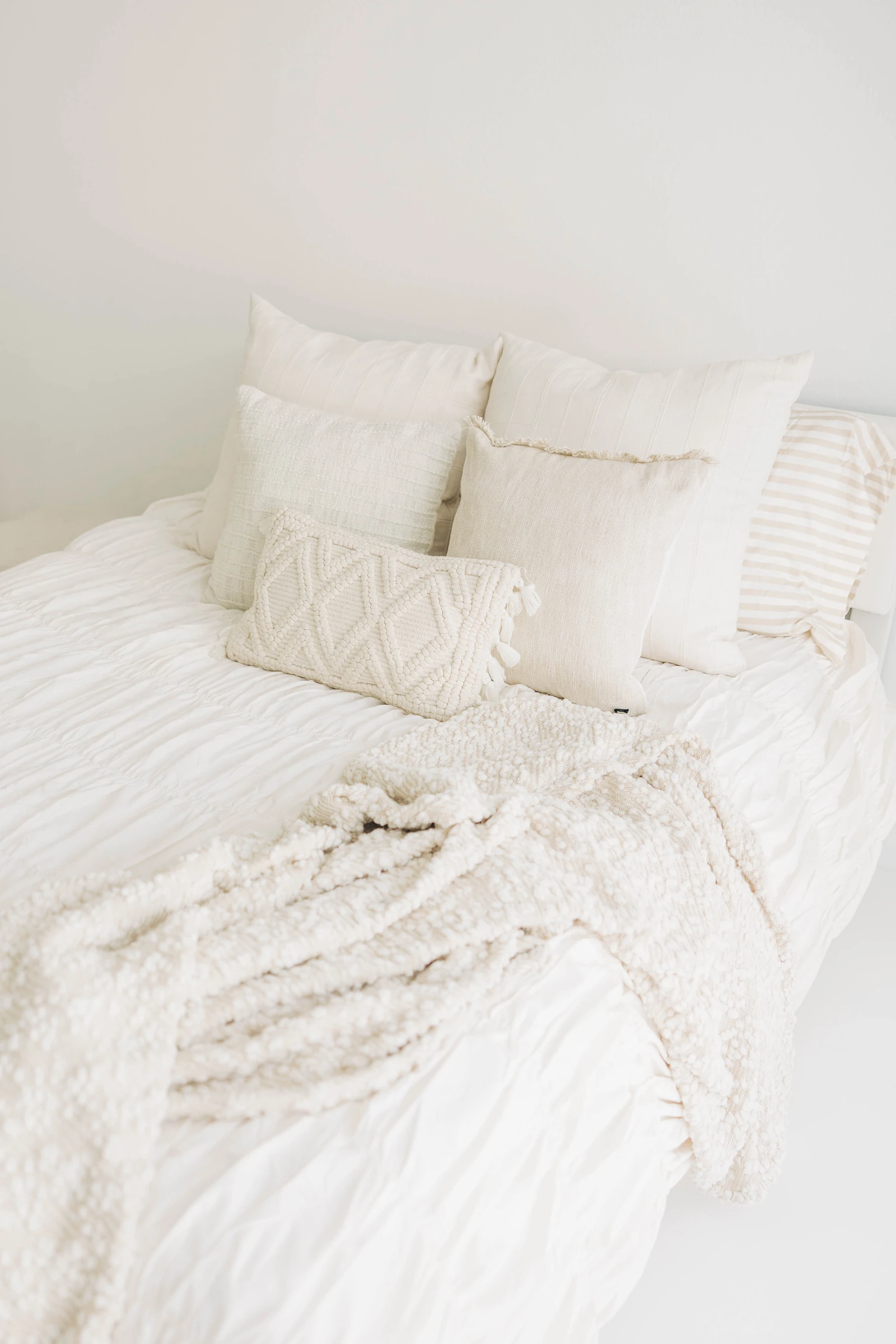 Warm layered textures on a styled bed in a natural-light studio, minutes from Longwood