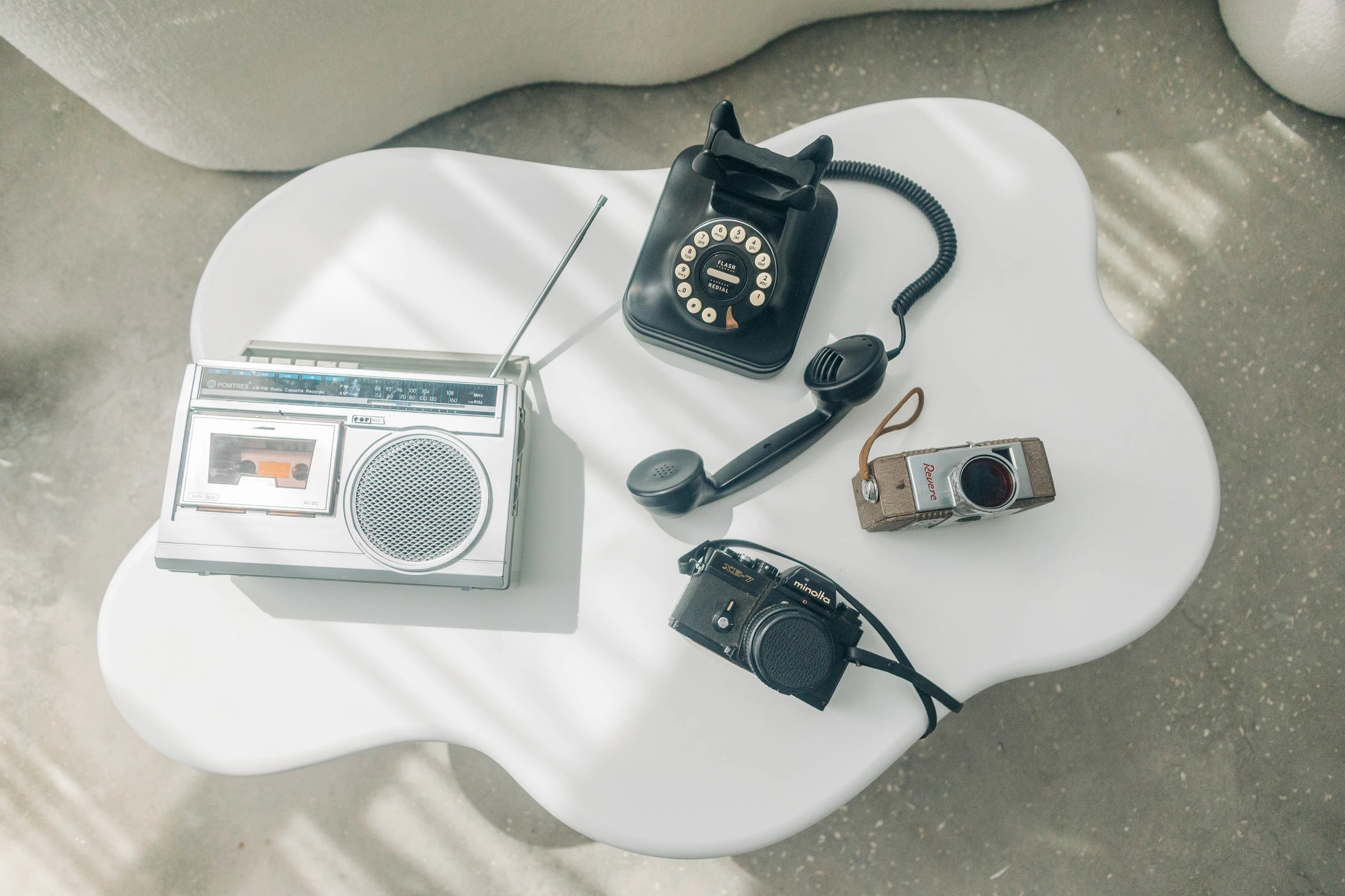 Retro props laid out on the studio's cloud table: rotary phone, boombox, and film cameras