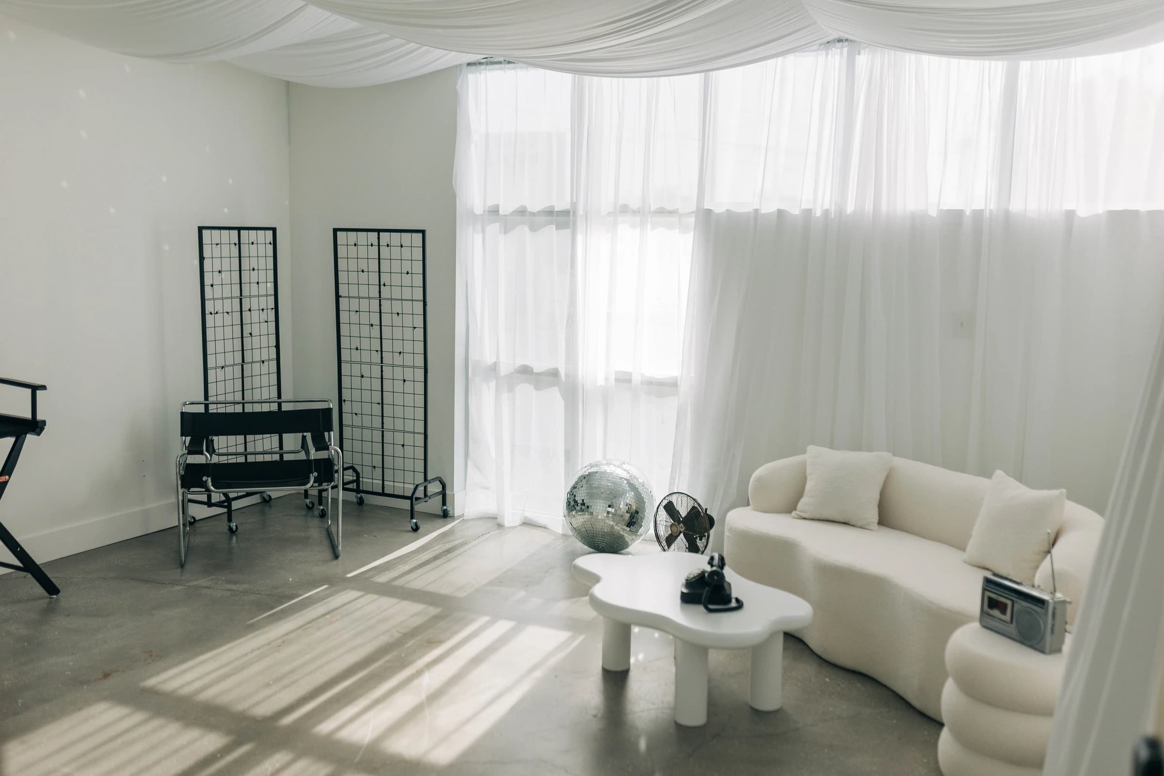 Studio B all at once: grid panels, the lounge, and morning sun through the sheers
