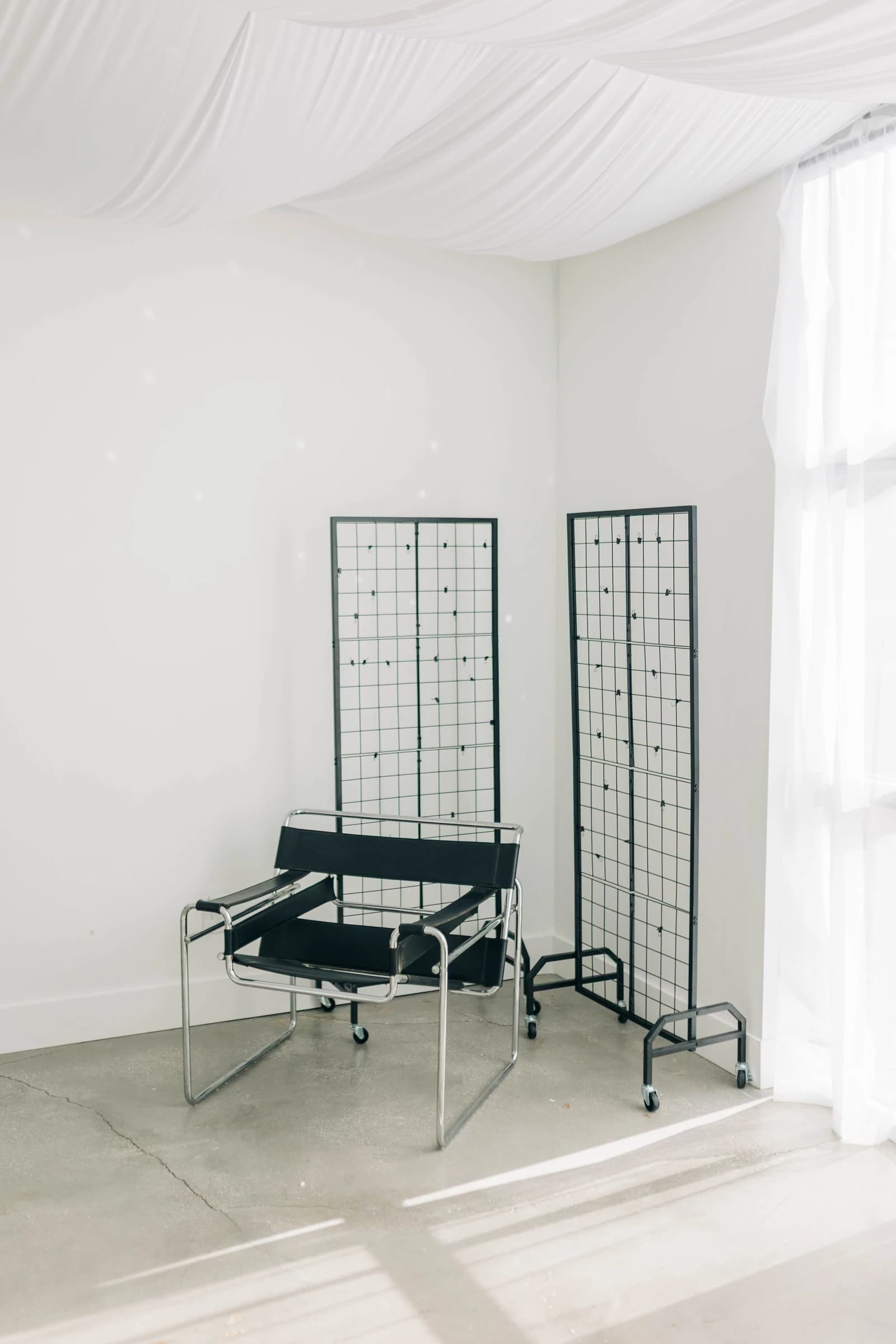 The black leather lounge chair and grid panels under Studio B's draped ceiling